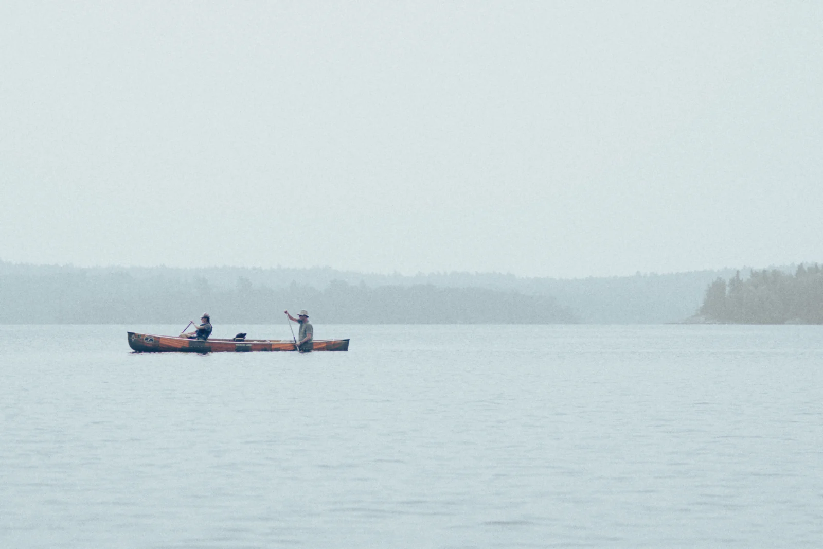 Two canoes crossing a hazy lake in the Boundary Waters.