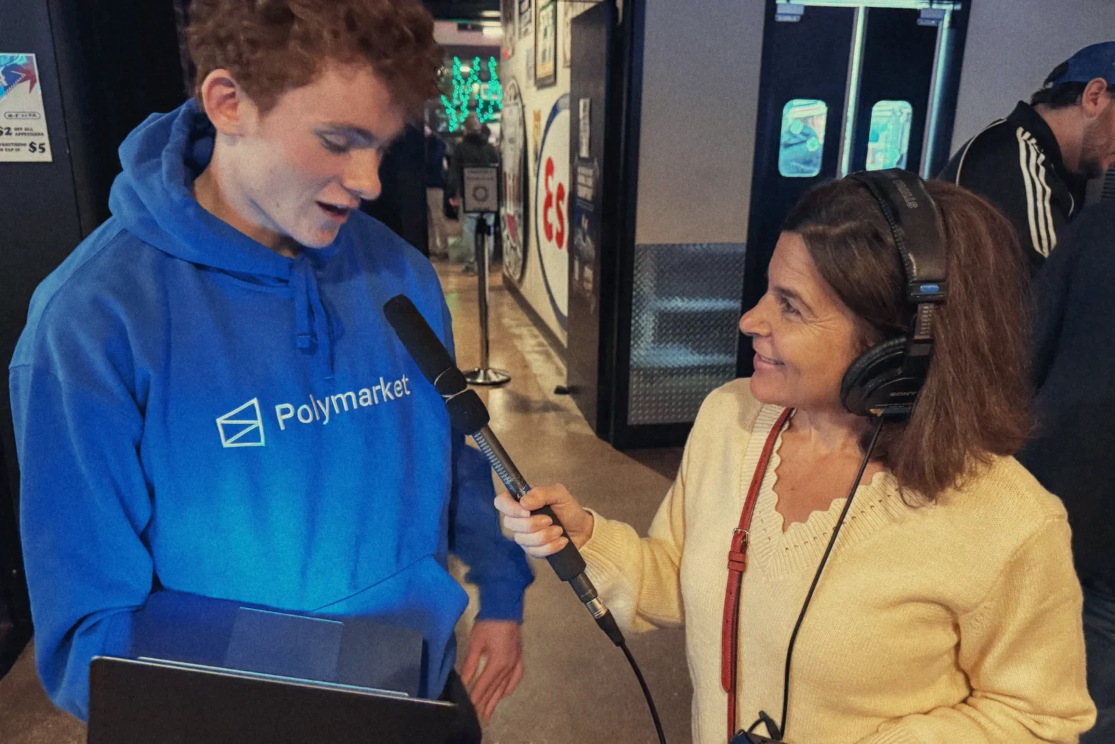 Me in a Polymarket hoodie, holding a laptop, answering a radio reporter's questions.
